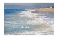 A sweep of blue green surf washes up on the California beach.