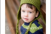A 2 year old poses for a portrait with an adorabel froggie hat.