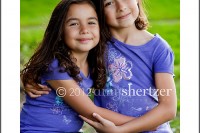 Adorable sisters in purple shirts give each other a sweet hug for a picture in Los Angeles..