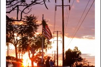 The setting sun makes a warm glow in the sky and through an American flag.